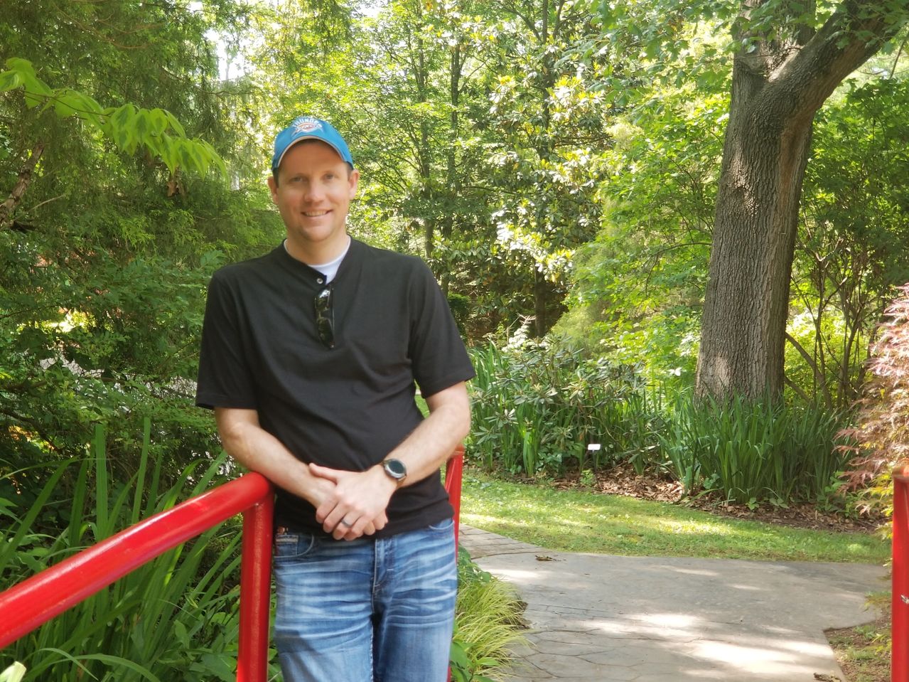 Justin smiling outdoors beside a red railing